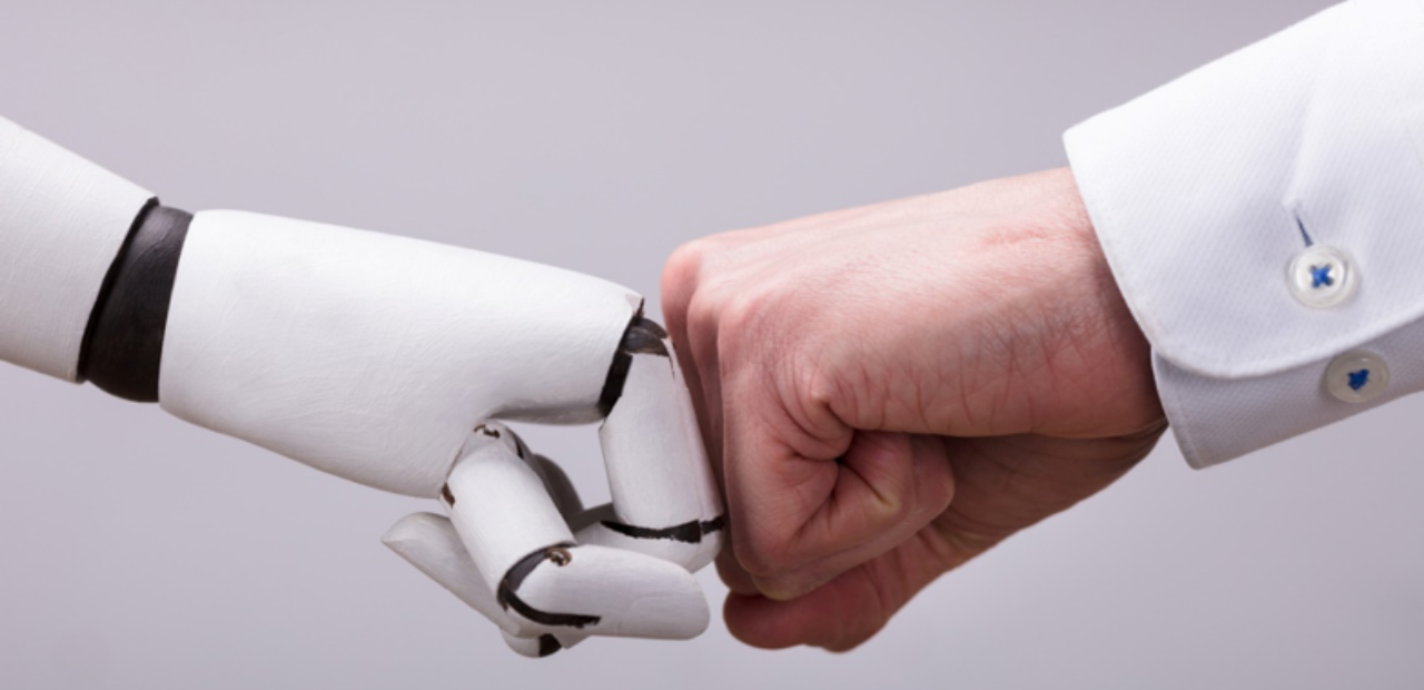 Human hand fist-bumping a robotic hand, collaboration between humans and AI, groundbreaking AI uses in the past five years.