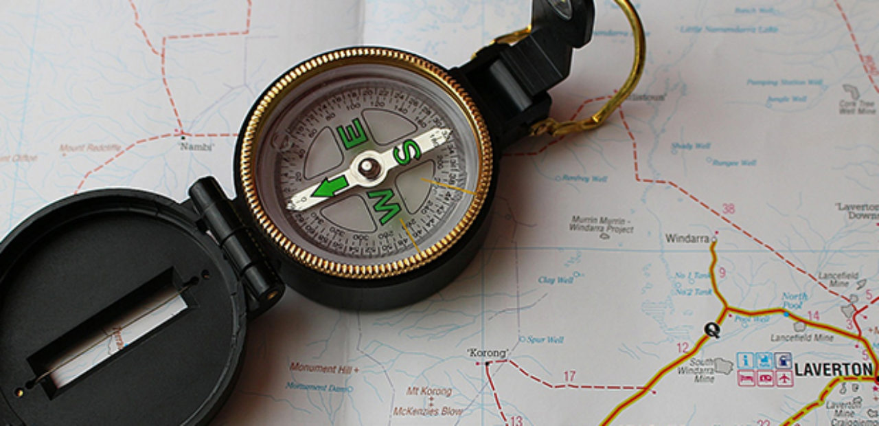 A compass lying on top of a map, symbolizing navigation and strategic direction in the context of developing a skilled workforce for systems engineering
