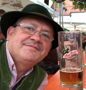 A man wearing traditional Bavarian clothing enjoying a beer in a beer garden. Herbert, Solution Architect. Zuken. 