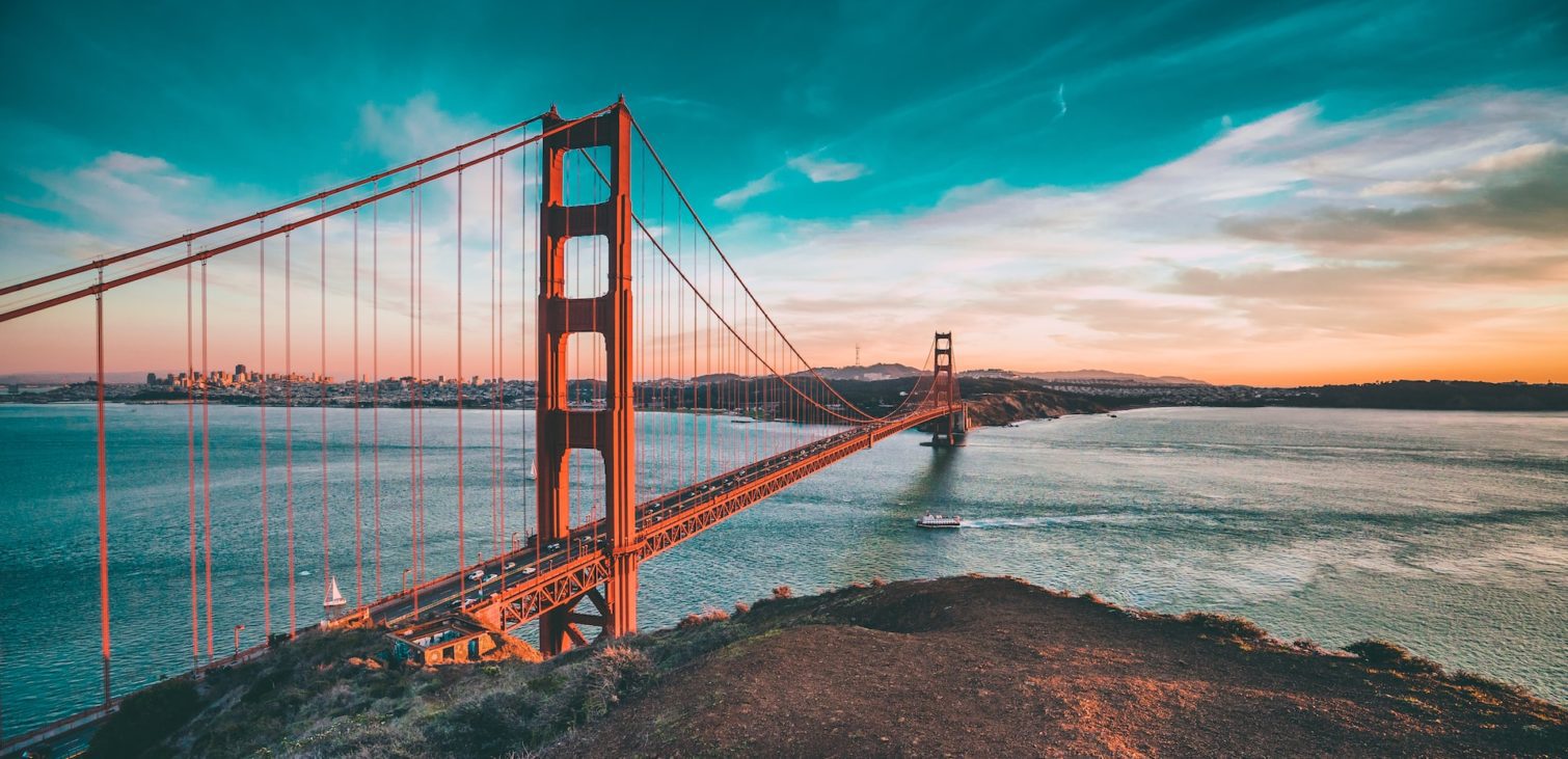 The Golden Gate Bridge at sunset, with vibrant colors in the sky reflecting on the water below, embodying a journey that connects historical architecture with the innovation hub of Silicon Valley