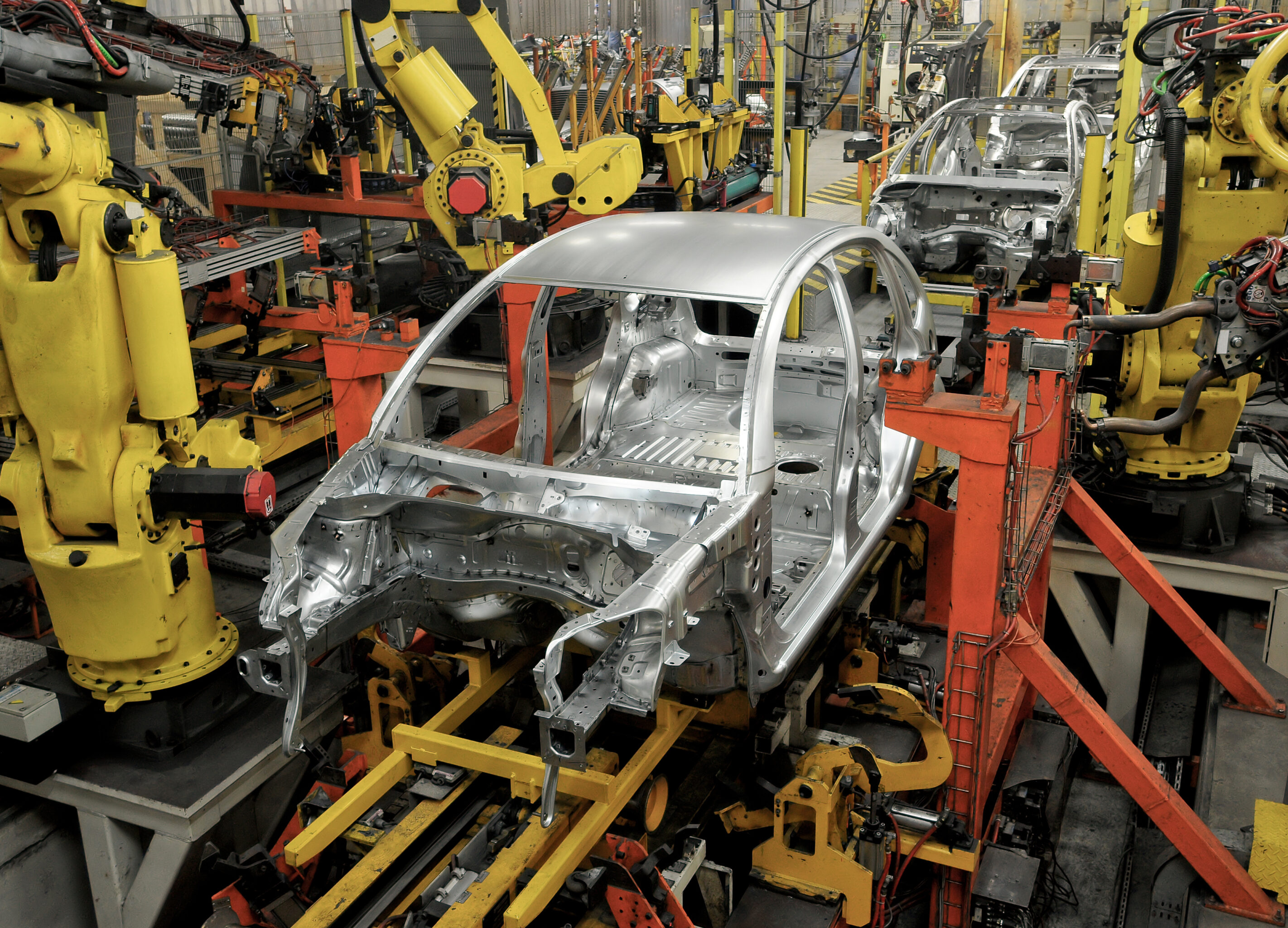 Vehicle chassis in manufacturing line with robotic arms