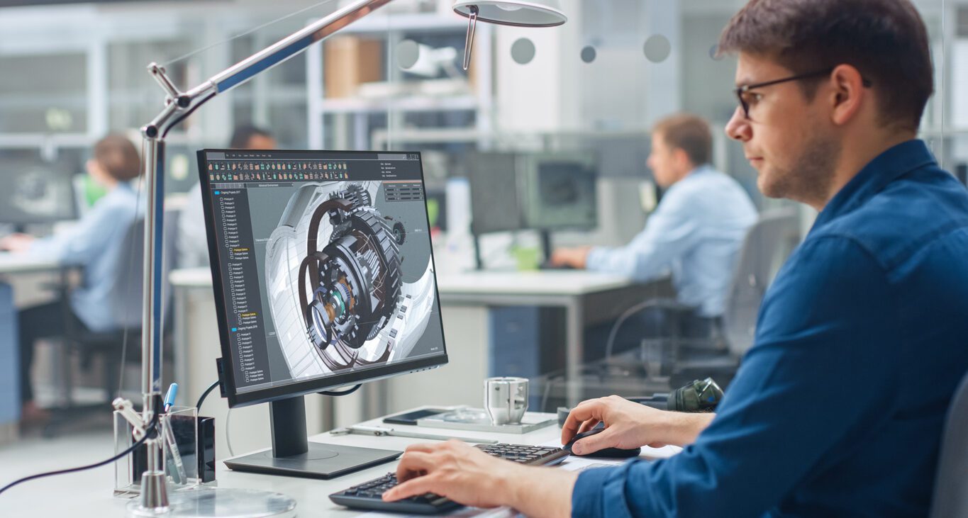 Engineer Working on Desktop Computer, Screen Showing CAD Software with Engine 3D Model.