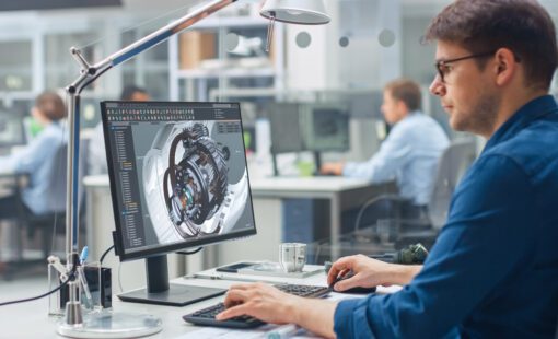Engineer Working on Desktop Computer, Screen Showing CAD Software with Engine 3D Model.