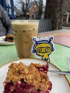 Coffee, pastry, and Zukie on an outdoor table during the Zeal Motors customer video shoot in Canada