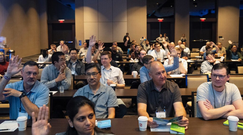 ZIW 2026 attendees raising their hands during a conference session.